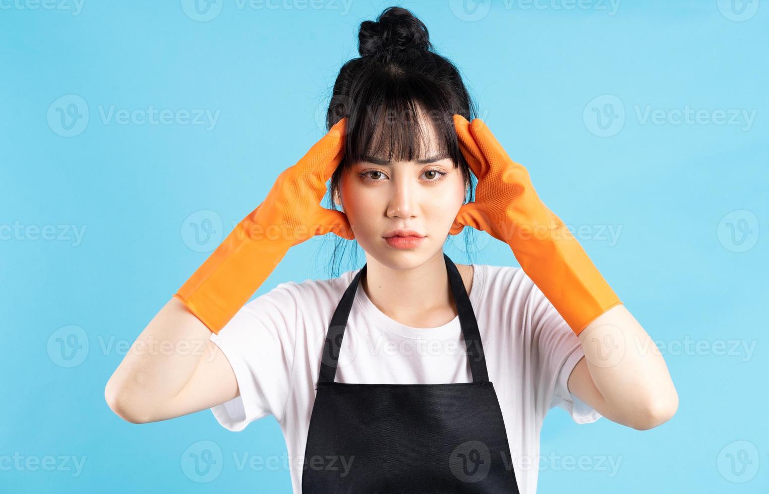 femme au foyer asiatique porte des gants orange et tient un jet d'eau dans sa main photo