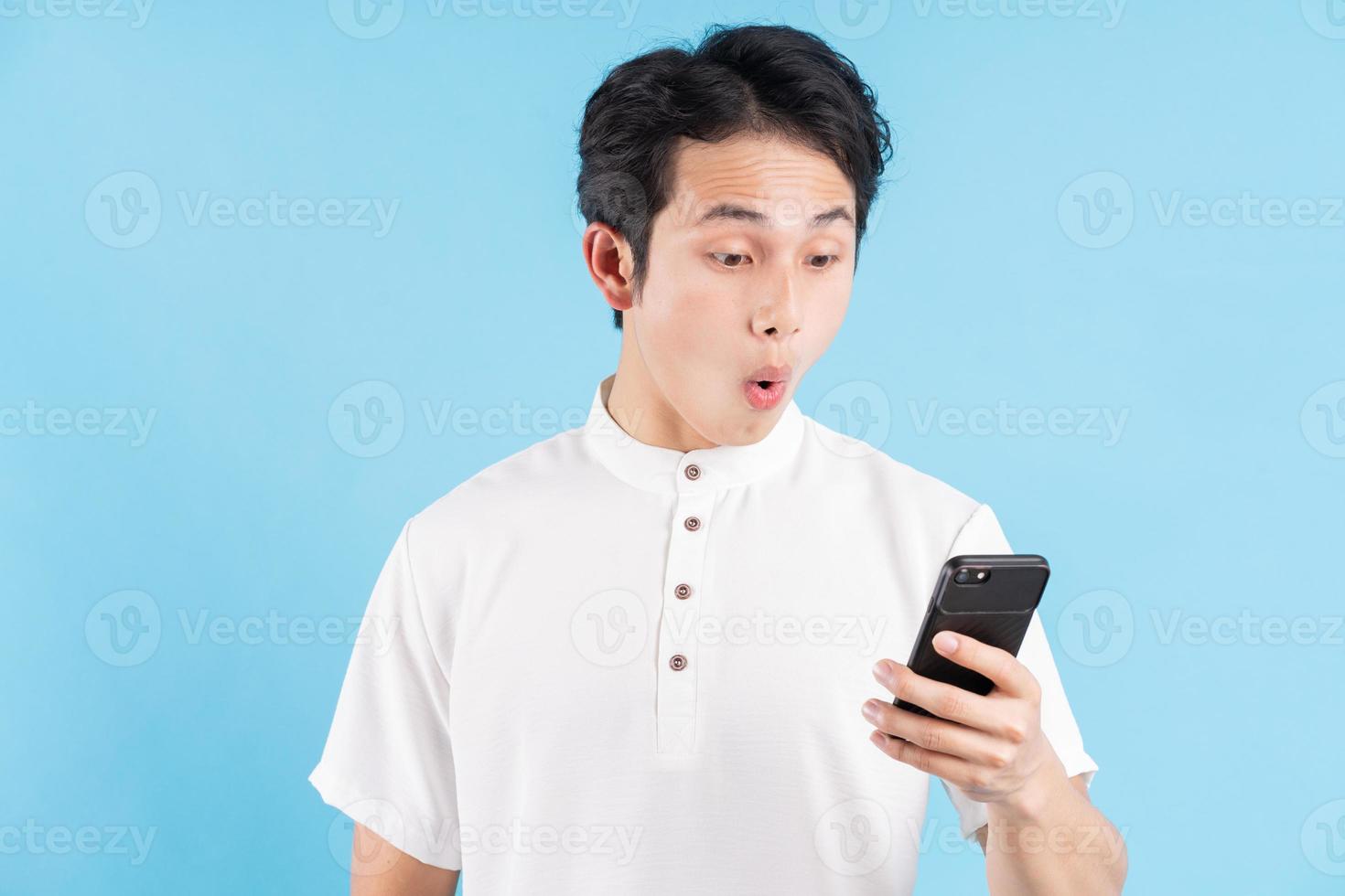 jeune homme tenant le téléphone et le regardant avec une expression surprise photo