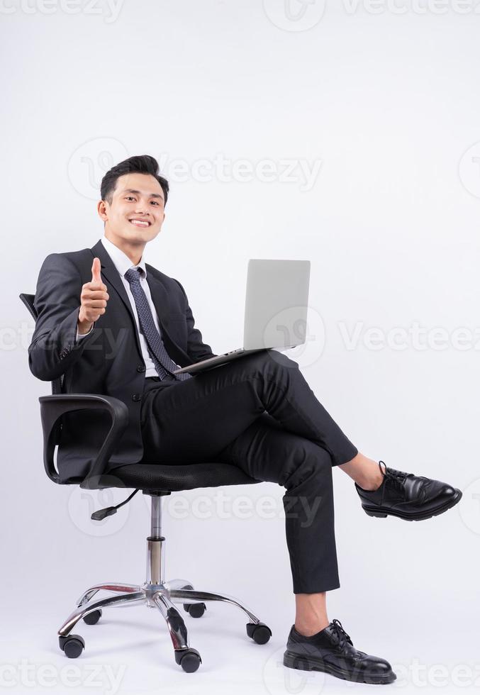 jeune homme d'affaires asiatique assis sur une chaise sur fond blanc photo