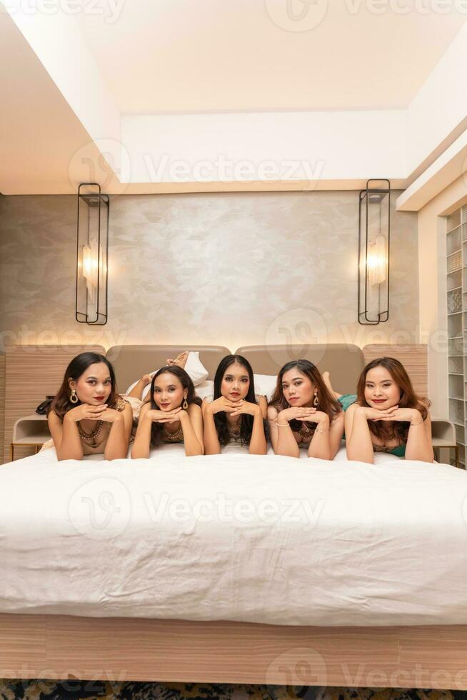 une groupe de asiatique femmes sont mensonge sur blanc matelas avec leur copains dans une Hôtel photo