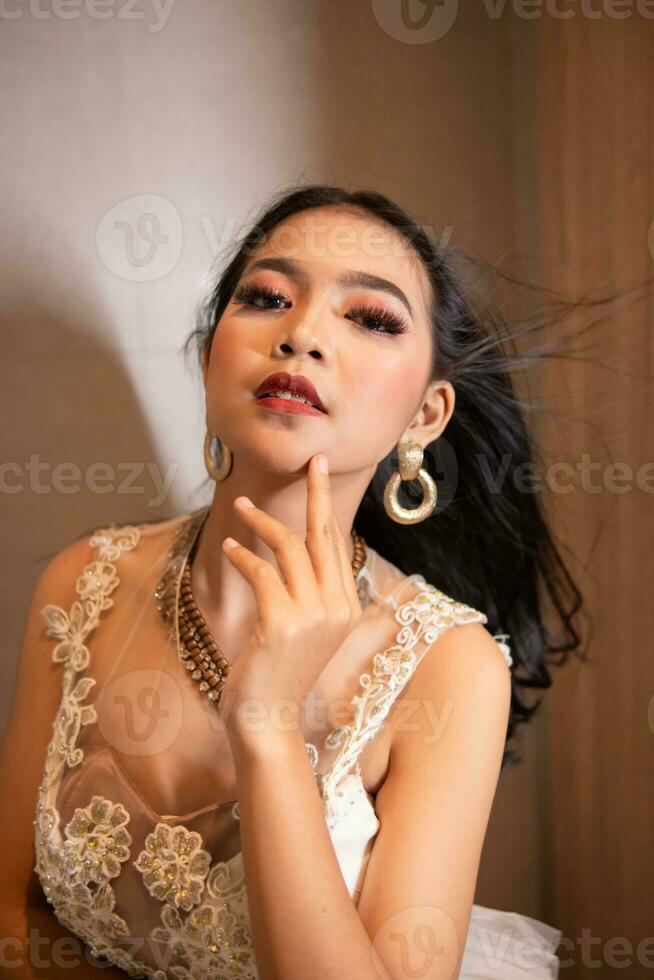 un asiatique femme avec une blanc robe et noir cheveux est posant sexy et élégant dans une Hôtel pièce photo