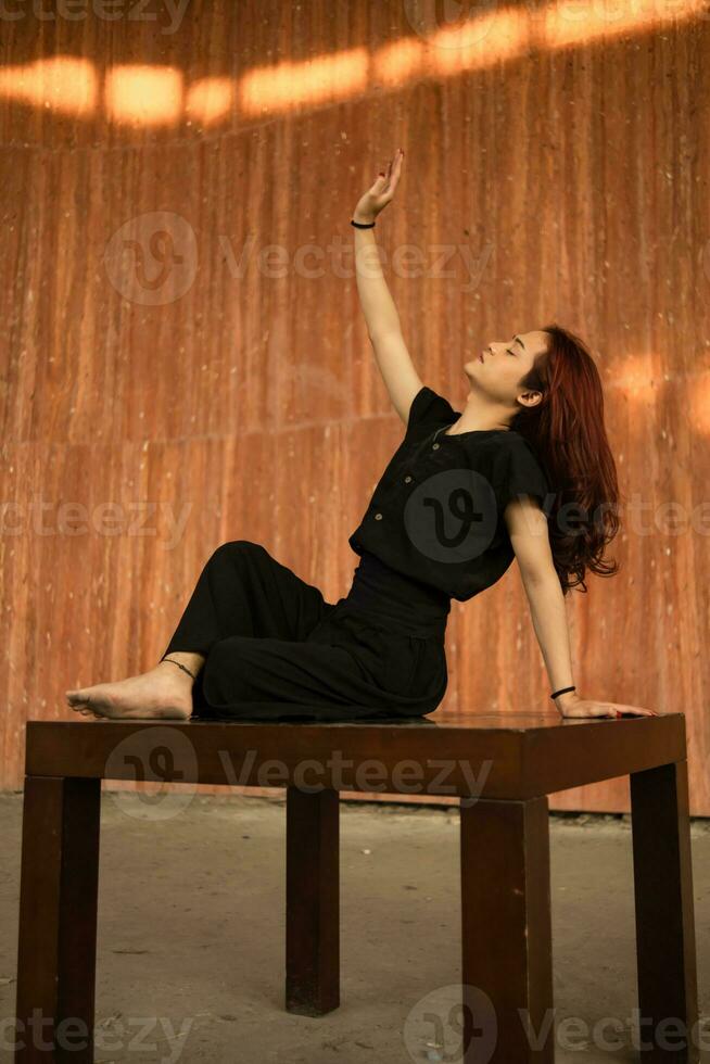 un asiatique homme avec longue cheveux est séance et posant sur une marron table photo