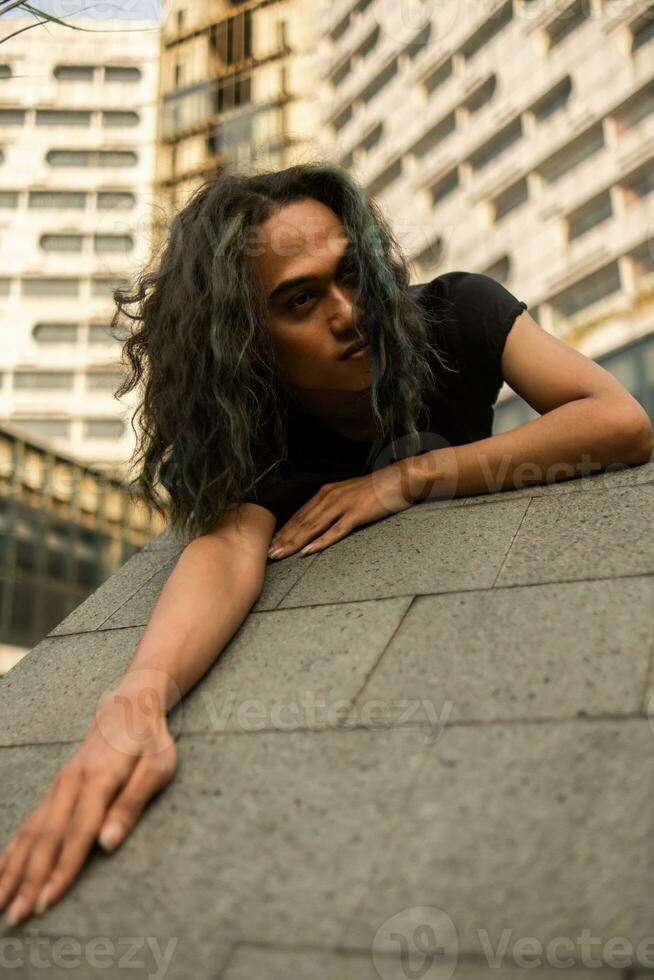 un asiatique homme dort sur une marbre Roche tandis que portant noir vêtements autour un vieux bâtiment photo