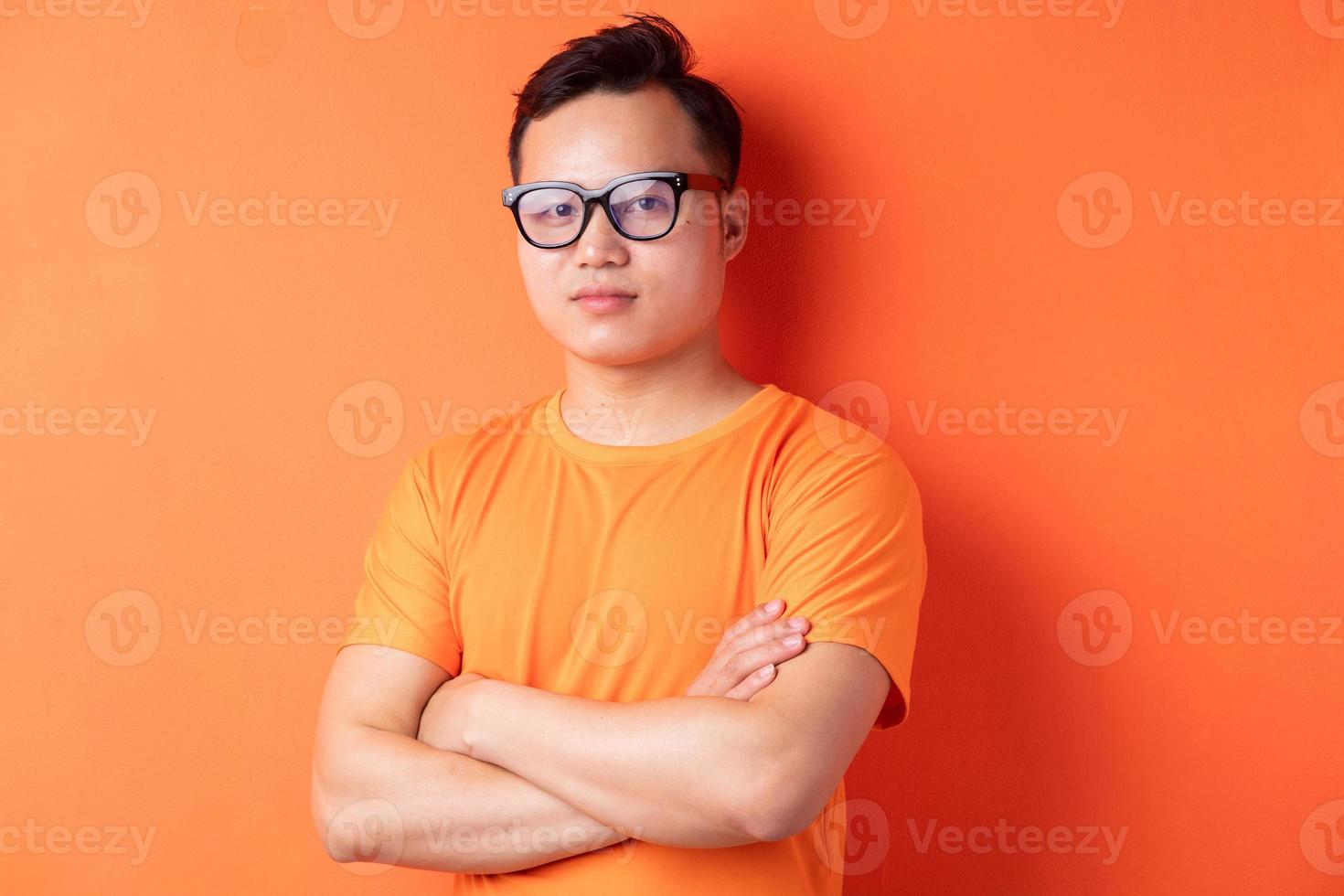 homme asiatique avec les bras croisés sur fond orange photo