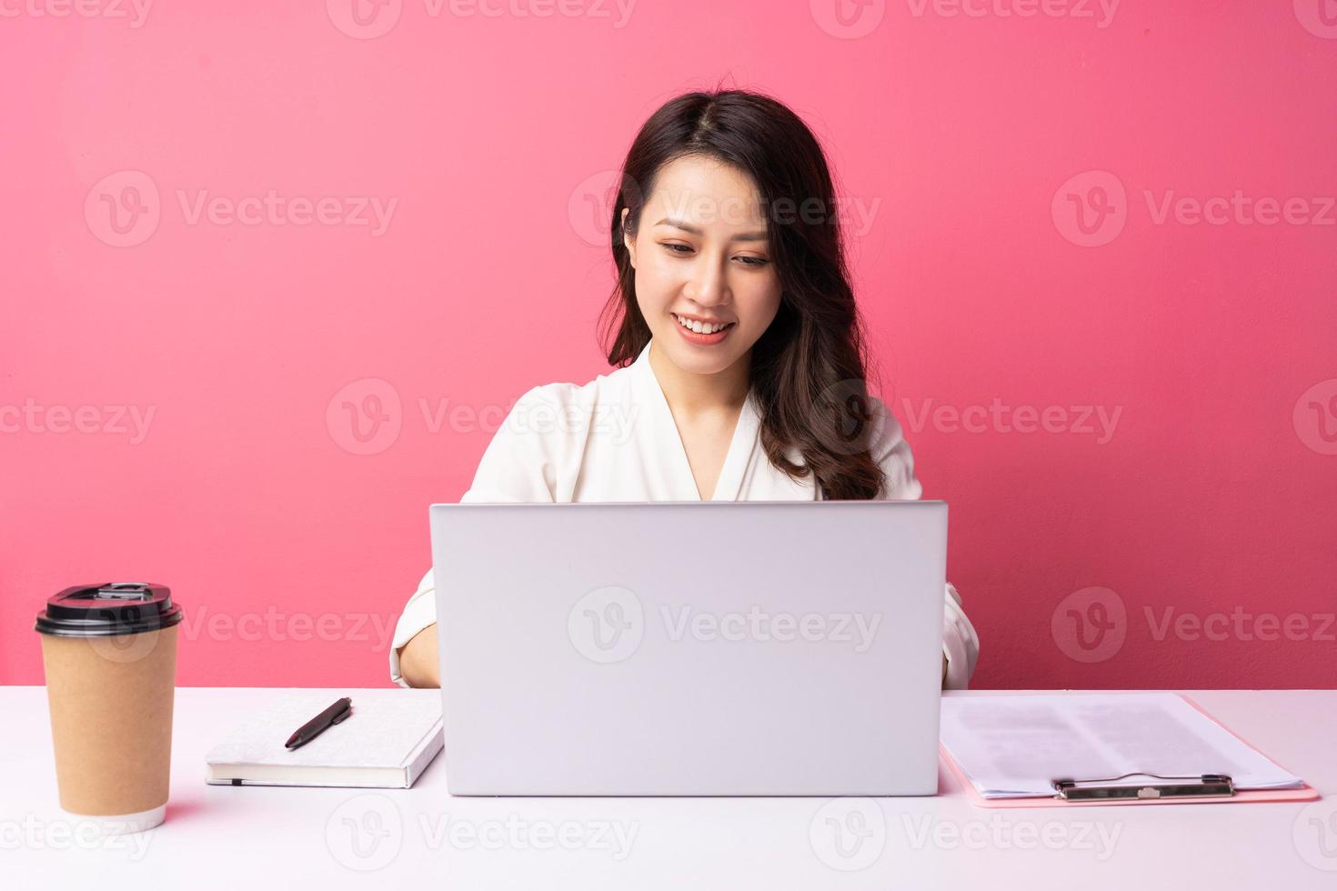 jeune femme d'affaires asiatique assise travaillant avec une expression sur fond photo
