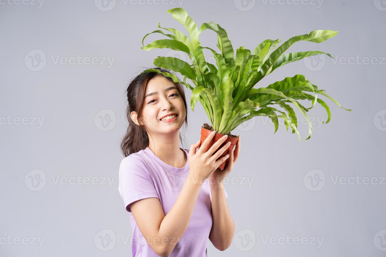 Jeune femme asiatique tenant un pot sur fond gris photo