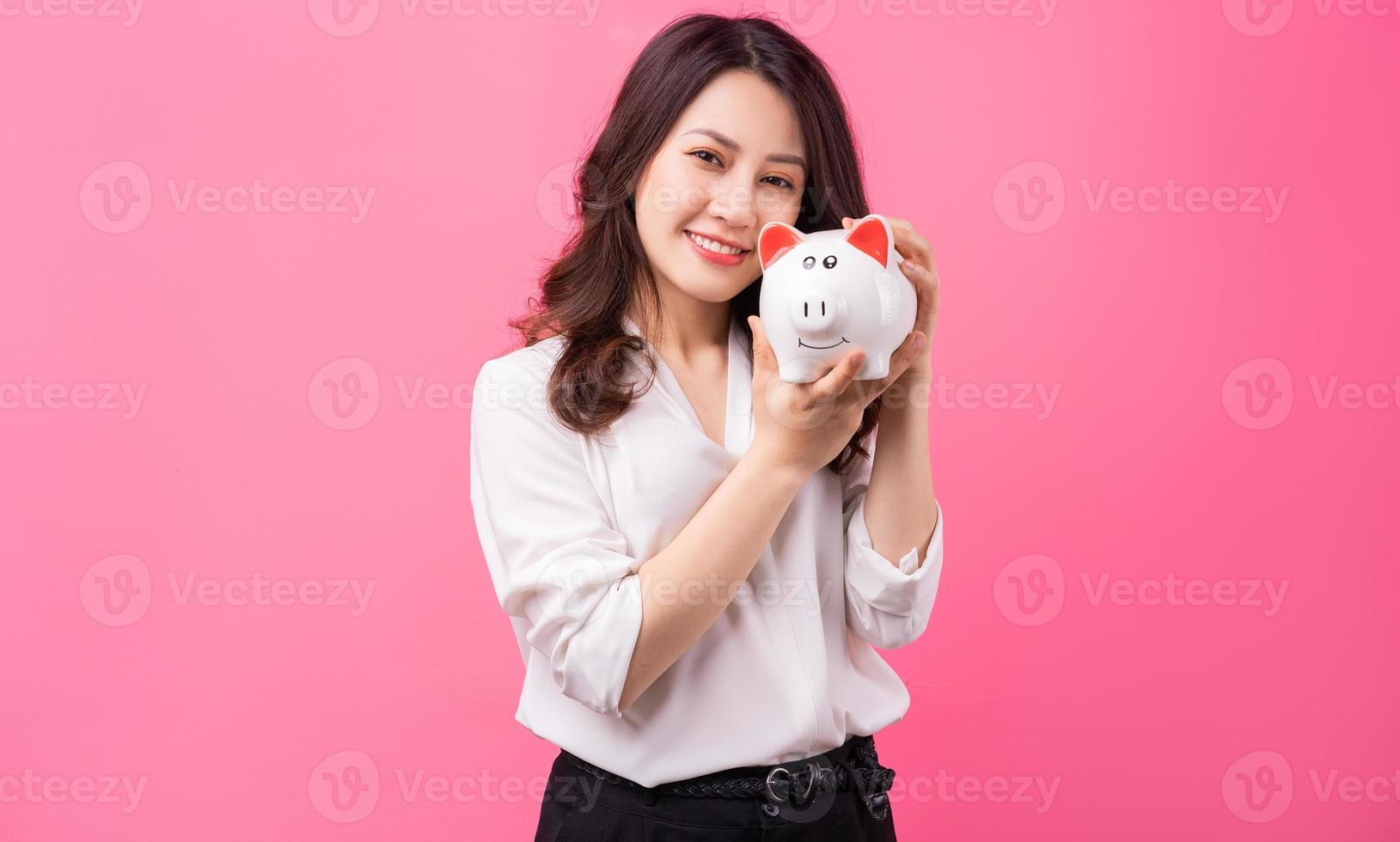 femme d'affaires asiatique tenant un cochon dans sa main, économisant de l'argent concept photo