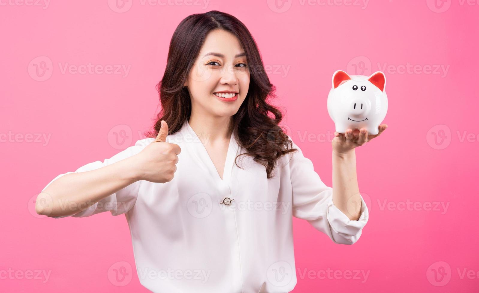 femme d'affaires asiatique tenant un cochon dans sa main, économisant de l'argent concept photo