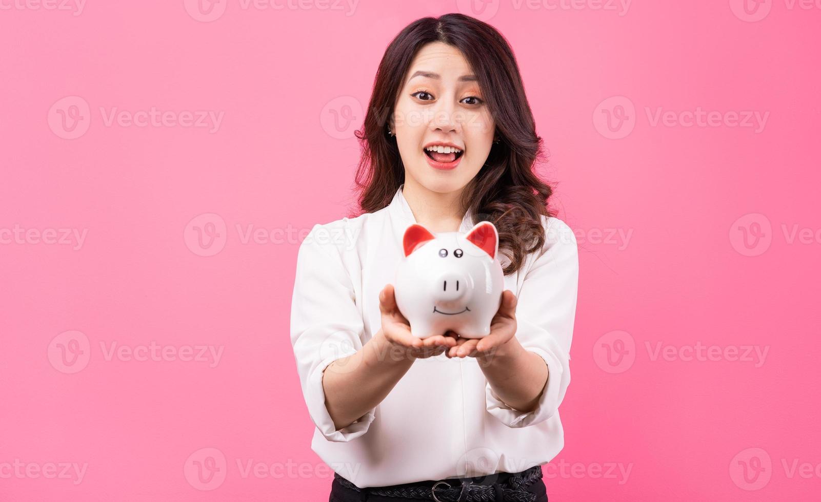 femme d'affaires asiatique tenant un cochon dans sa main, économisant de l'argent concept photo