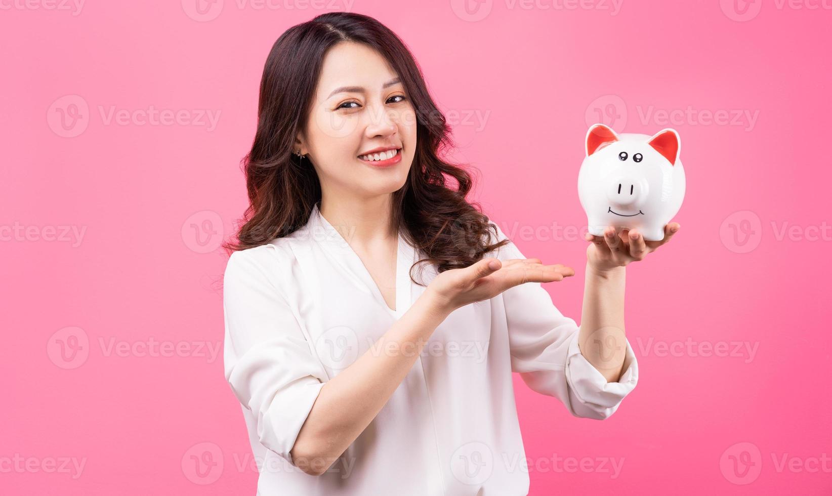 femme d'affaires asiatique tenant un cochon dans sa main, économisant de l'argent concept photo