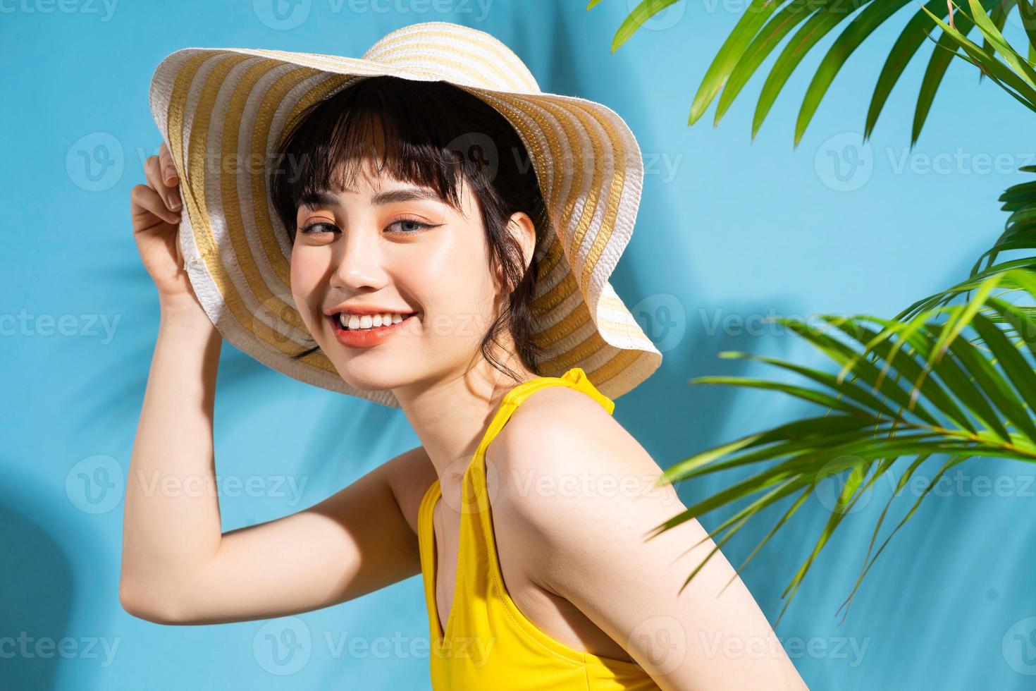 belle femme asiatique portant une combinaison jaune sur fond bleu et concept d'été photo