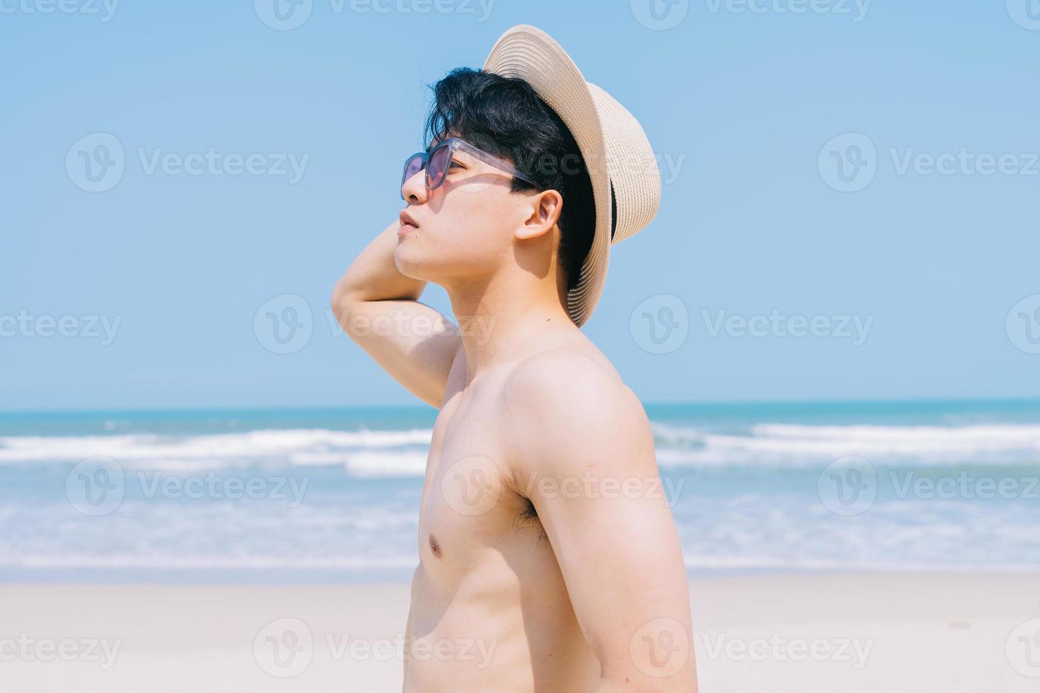 jeune homme asiatique marchant sur la plage photo