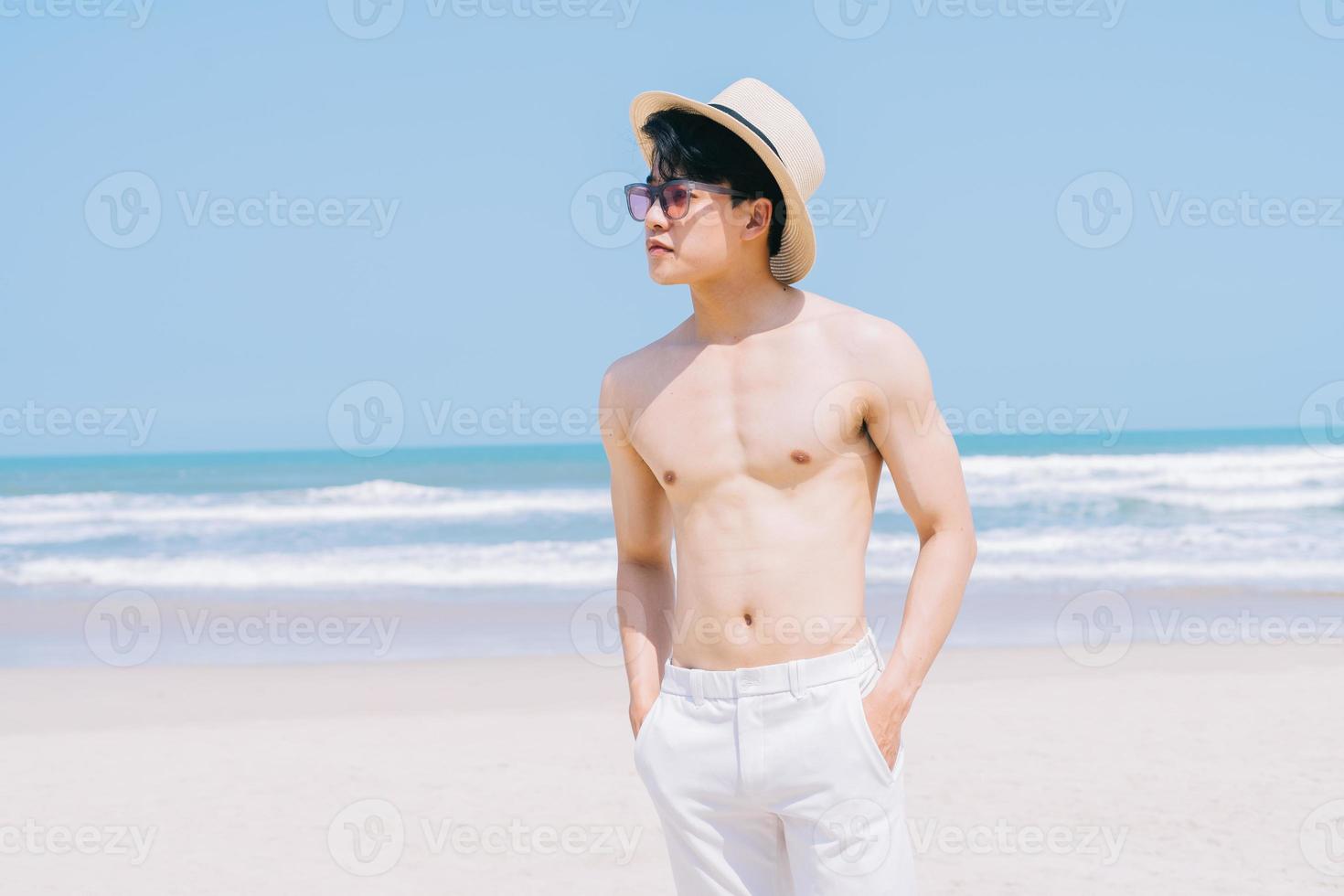 jeune homme asiatique marchant sur la plage photo