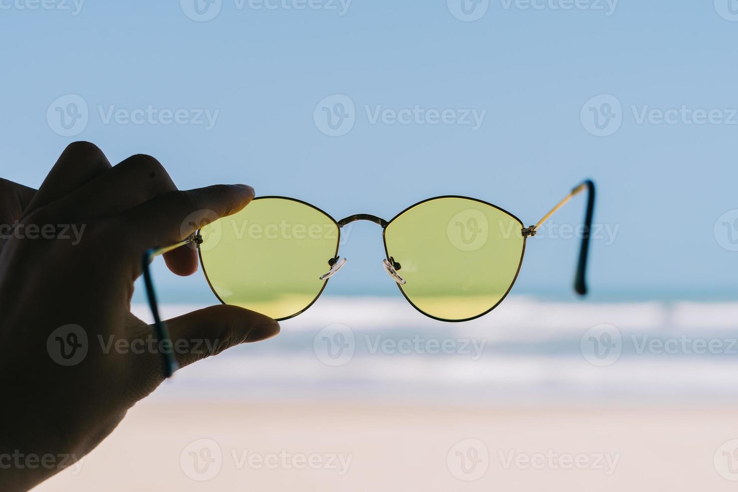 une main tenait des lunettes de soleil jaunes photo