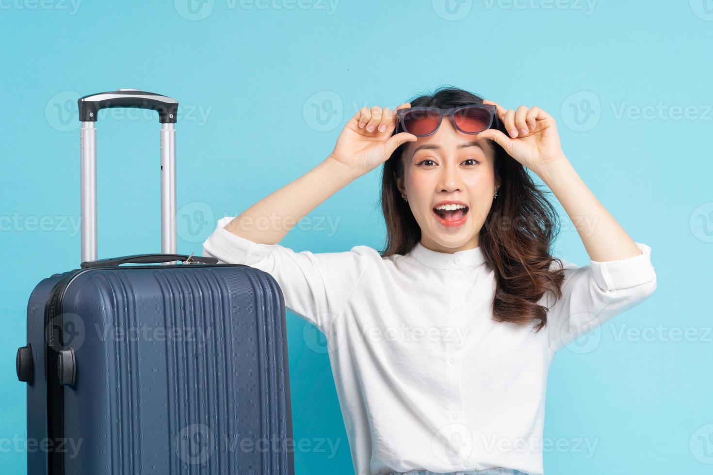 belle femme asiatique assise posant à côté de la valise et se préparant à voyager photo
