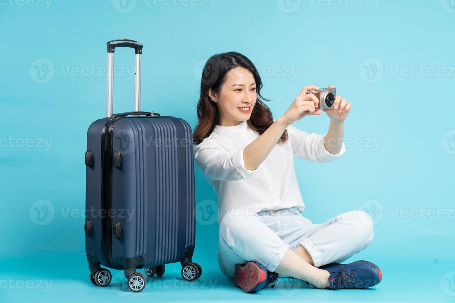 belle femme asiatique assise posant à côté de la valise et se préparant à voyager photo