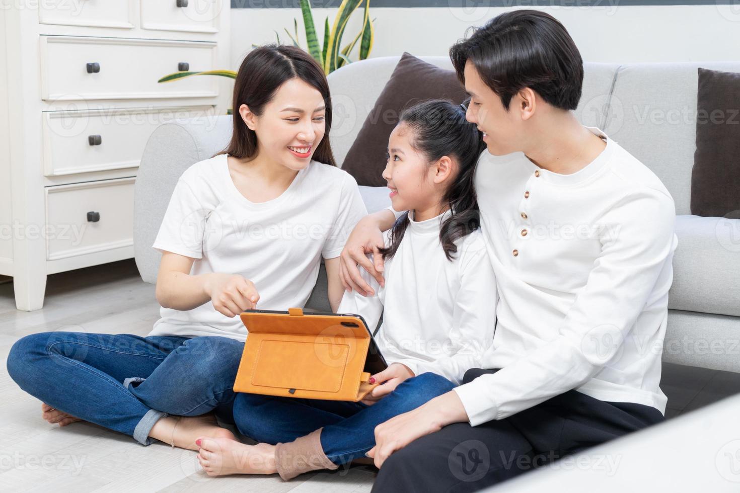 les parents asiatiques guident leur fille à utiliser la tablette photo