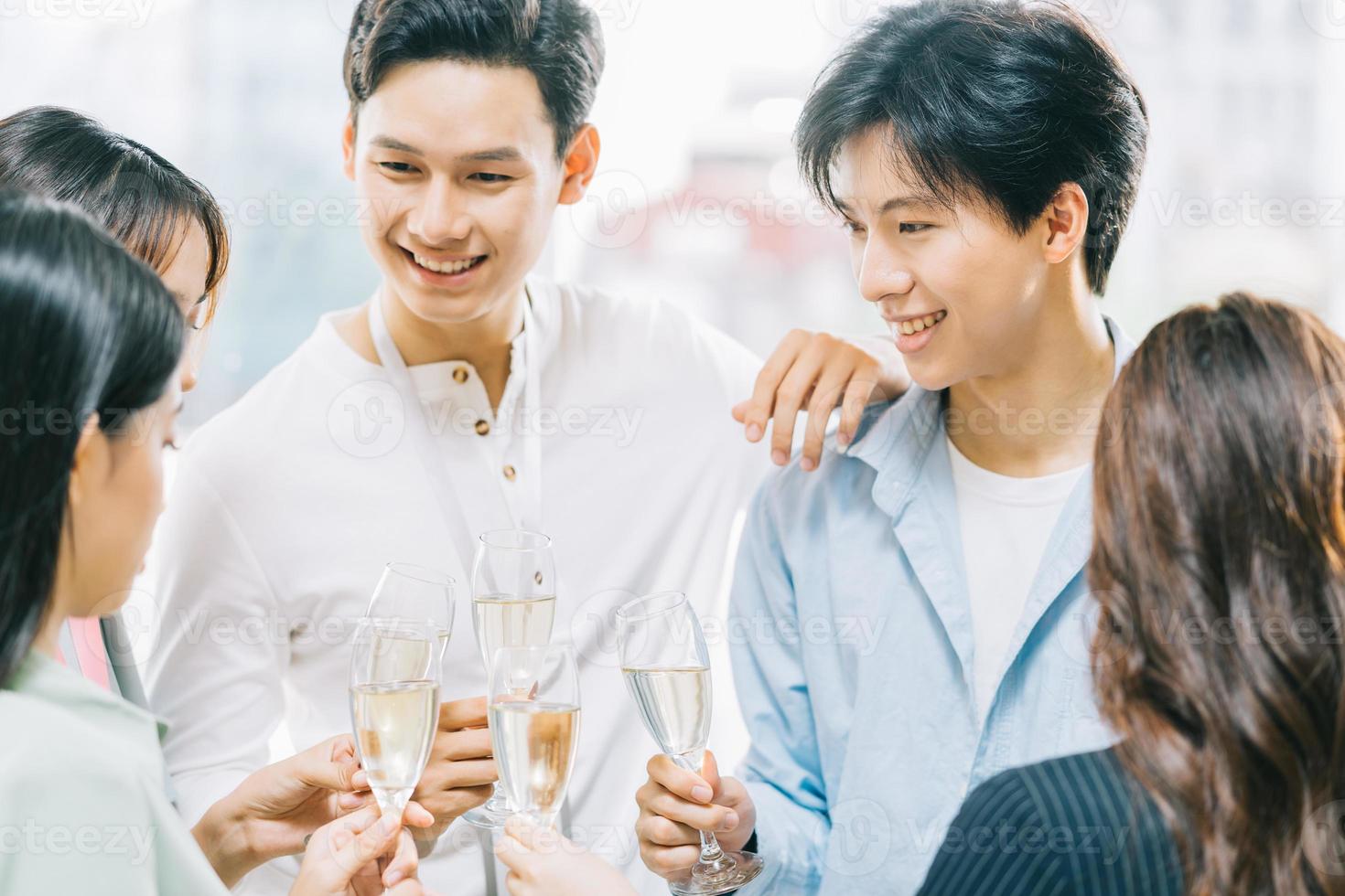 des hommes d'affaires asiatiques du groupe portent un toast ensemble et discutent lors d'une fête d'entreprise photo