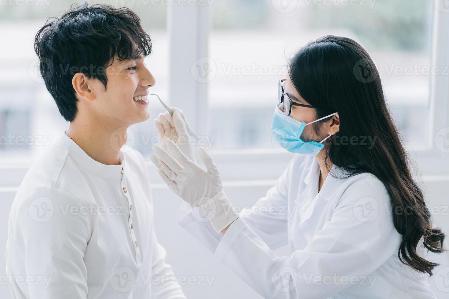 femme médecin asiatique vérifiant les dents d'un patient photo
