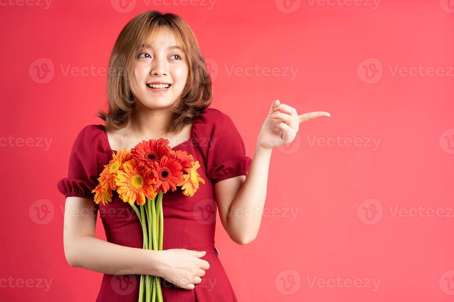 Jeune fille tenant un bouquet de gerberas avec une expression joyeuse sur fond photo