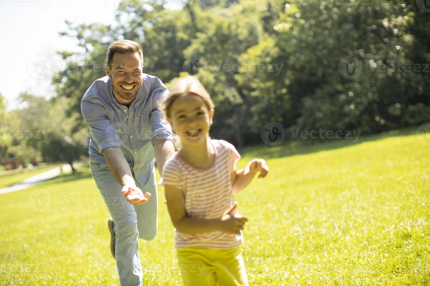 père pourchassant sa petite fille en jouant dans le parc photo