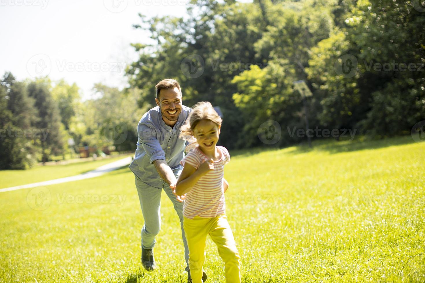 père pourchassant sa petite fille en jouant dans le parc photo