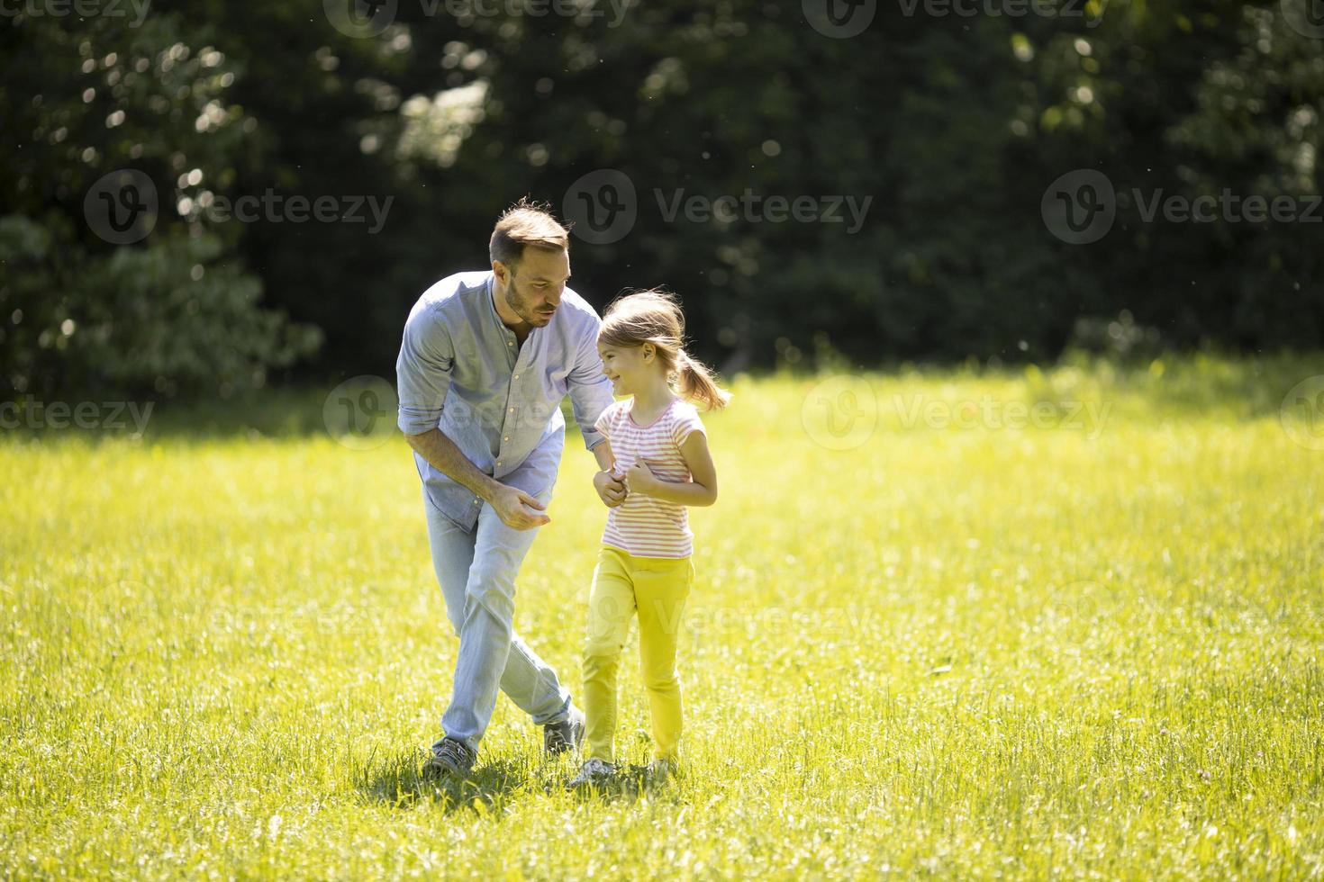 père pourchassant sa petite fille en jouant dans le parc photo