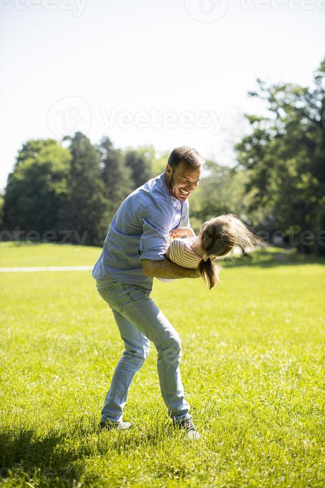 père avec fille s'amusant sur l'herbe au parc photo