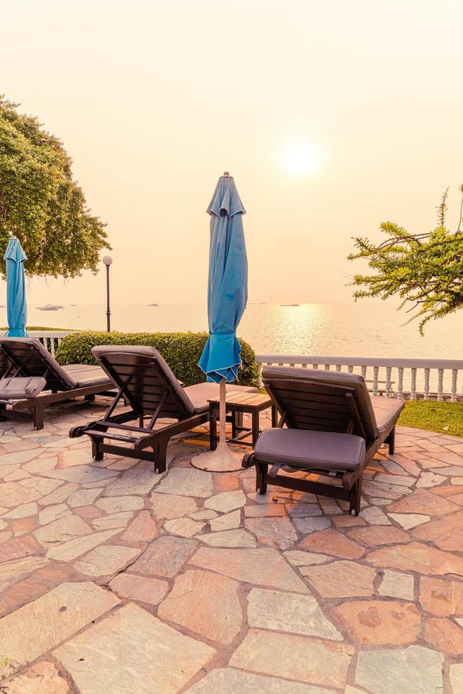 chaises de plage ou lits de piscine avec parasols autour de la piscine au coucher du soleil photo