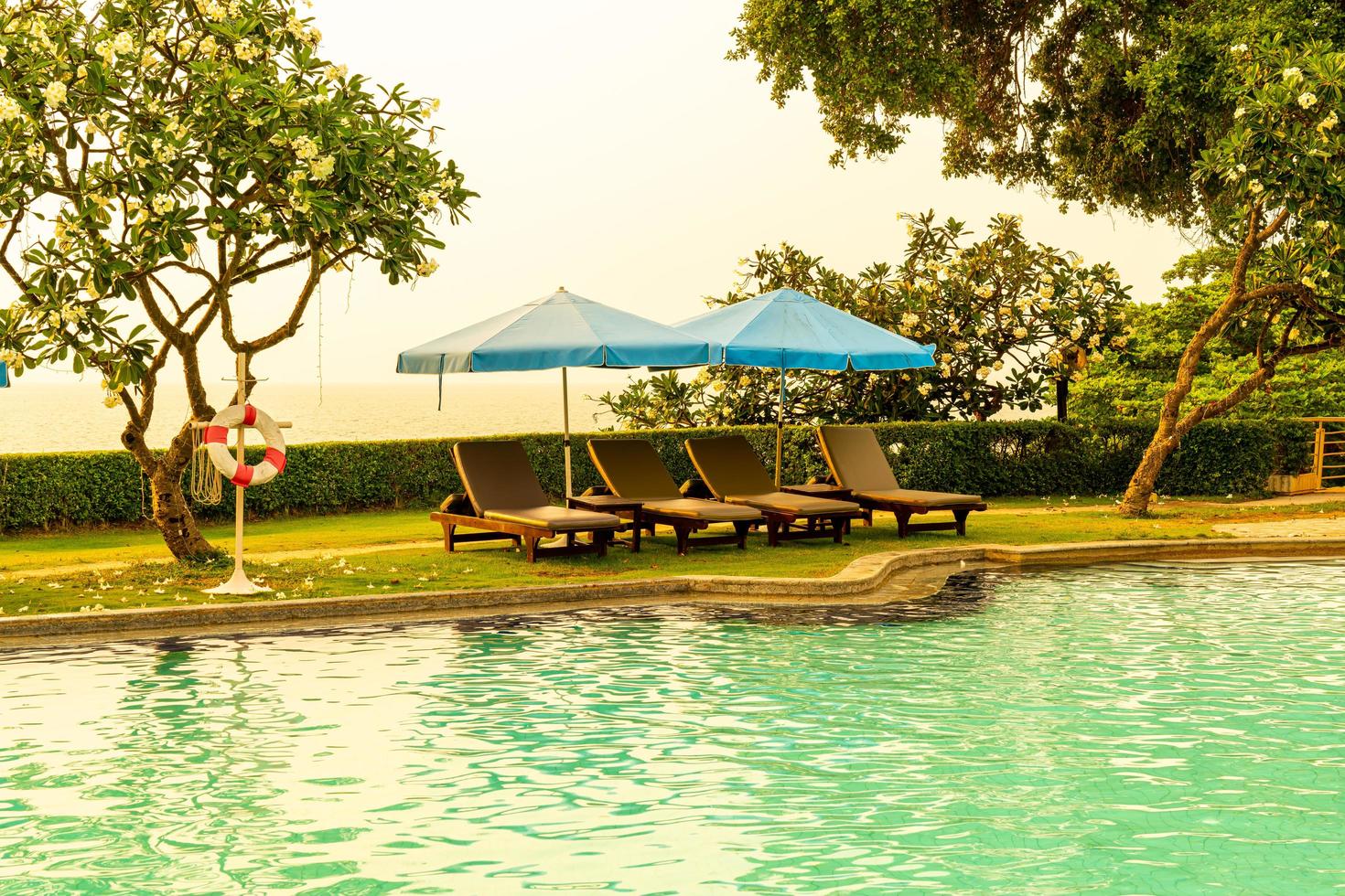 chaises de plage ou lits de piscine avec parasols autour de la piscine au coucher du soleil photo