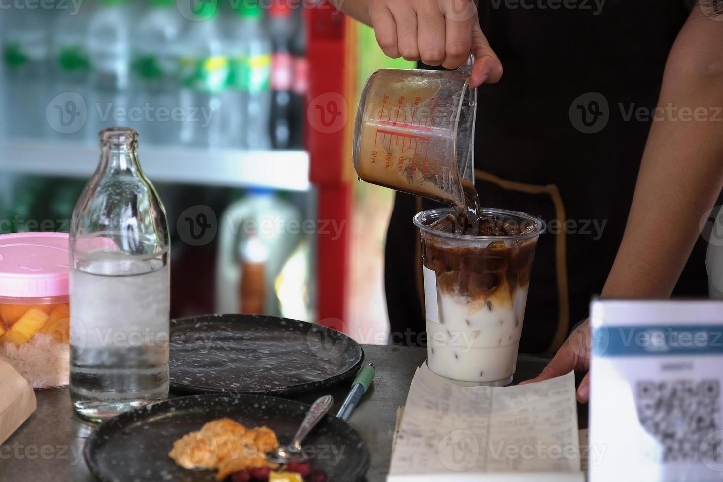 les employés mettent du café dans des verres pour faire du café au lait pour les clients. photo