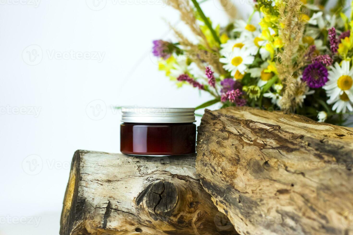 une pot de crème sur le Contexte de une sec souche, arbre écorce et une bouquet de sauvage fleurs. élégant apparence, mise en page, personnalité. bannière, une endroit pour le texte. photo