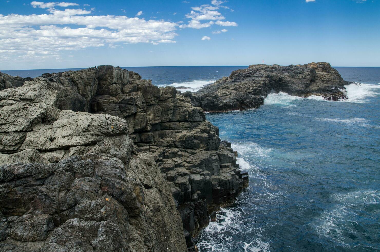 Naturel côtier Roche surface avec nuageux ciel et bleu océan l'eau dans Kiama, un de le principale touristique attractions dans Nouveau Sud Pays de Galles, Australie. photo