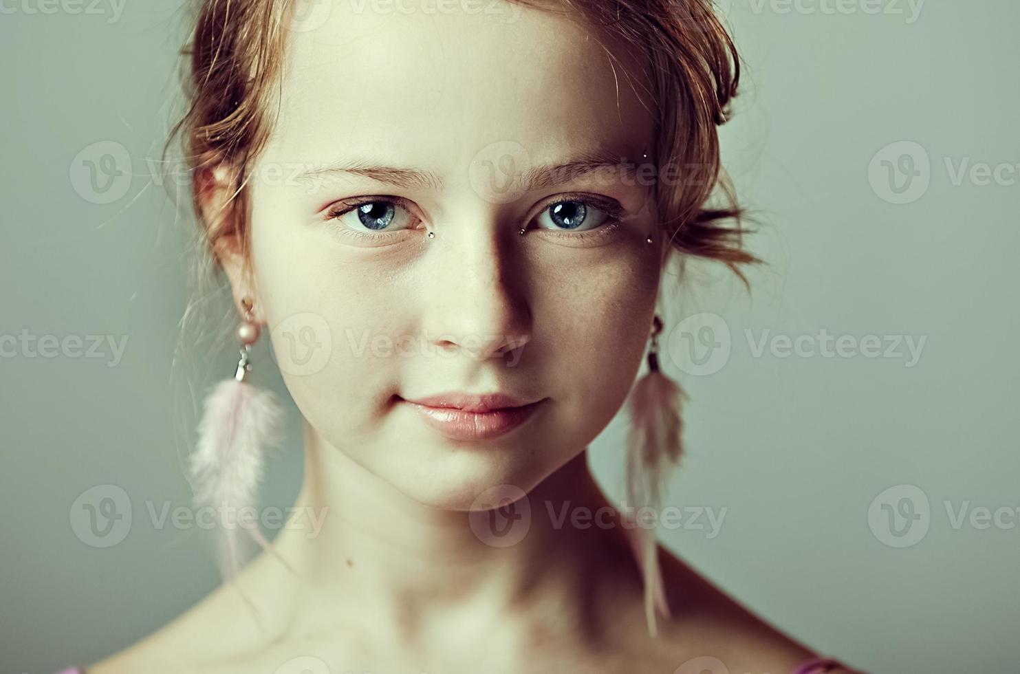 portrait en gros plan d'une jeune fille avec un maquillage festif pour une fête. La Saint-Valentin. boucles d'oreilles-plumes aux oreilles du modèle photo