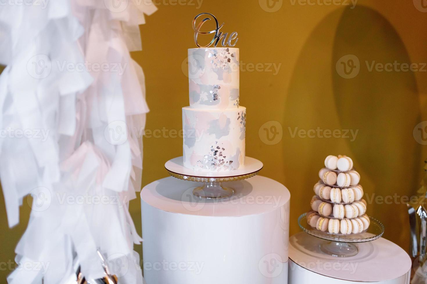 décoration pour le premier anniversaire avec un gâteau à deux étages et une barre chocolatée avec du macaron ou des macarons. fête d'anniversaire. mise au point sélective photo