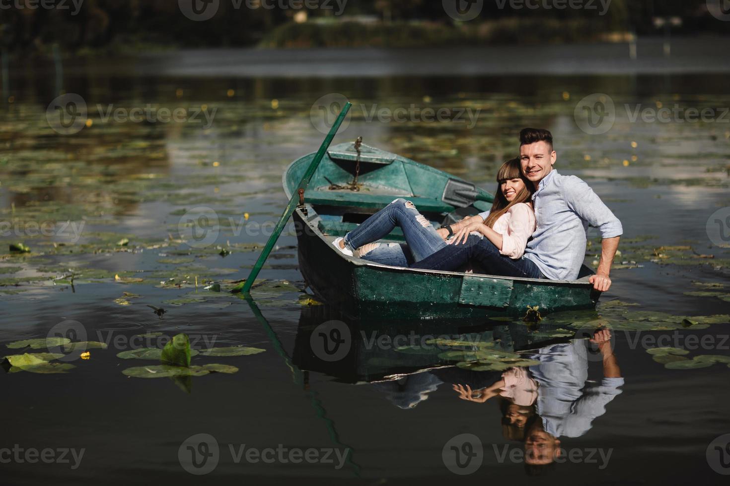 simplement se détendre. beau jeune couple profitant d'un rendez-vous romantique en ramant un bateau. couple d'amoureux se reposant sur un lac tout en conduisant un bateau vert. romance. photo