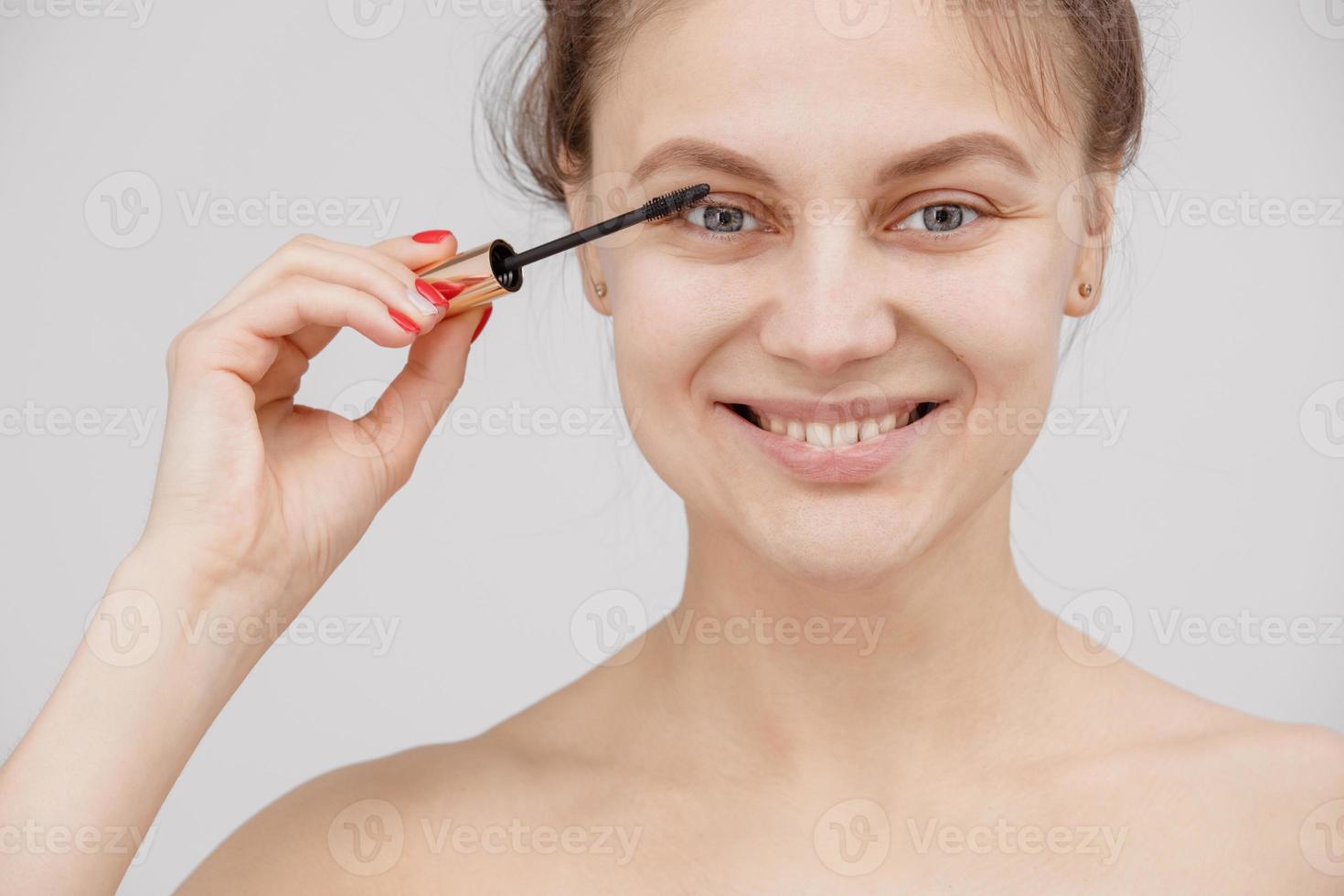 belle femme brune peint les cils. beau visage de femme. détail de maquillage. fille de beauté avec une peau parfaite photo