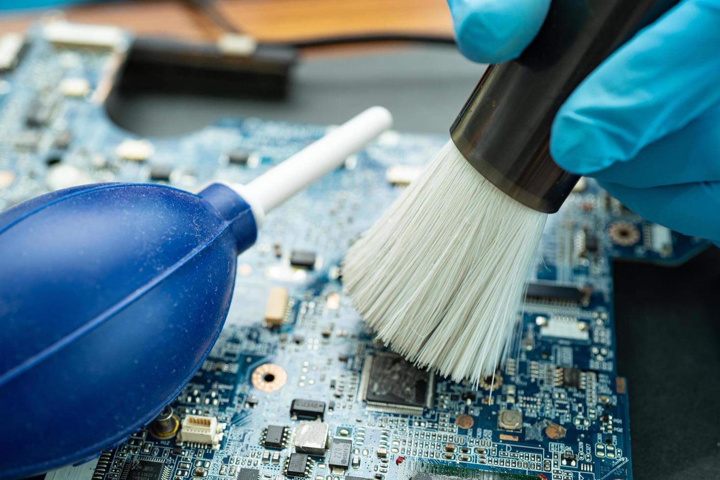 Le technicien utilise une brosse et une boule de soufflage d'air pour nettoyer la poussière dans l'ordinateur à circuit imprimé. technologie de mise à niveau et de maintenance des réparations. photo