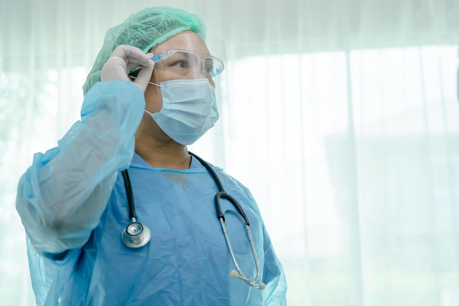 médecin asiatique portant un écran facial et un costume d'EPI nouvelle norme pour vérifier que le patient protège l'infection de sécurité covid 19 épidémie de coronavirus dans la salle d'hôpital de quarantaine. photo