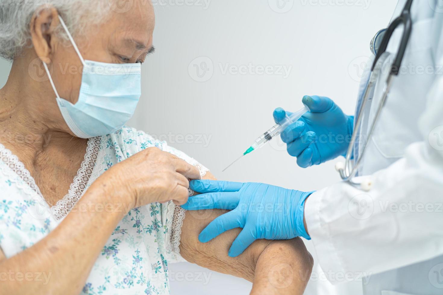 une femme âgée asiatique âgée portant un masque facial recevant un vaccin contre le covid-19 ou le coronavirus par un médecin fait une injection. photo