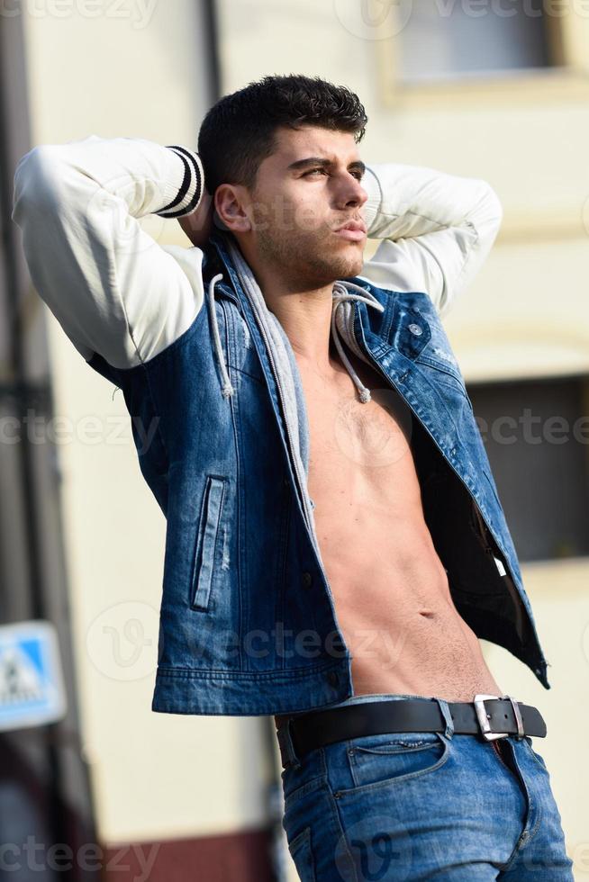 beau jeune homme aux yeux bleus posant en arrière-plan urbain photo