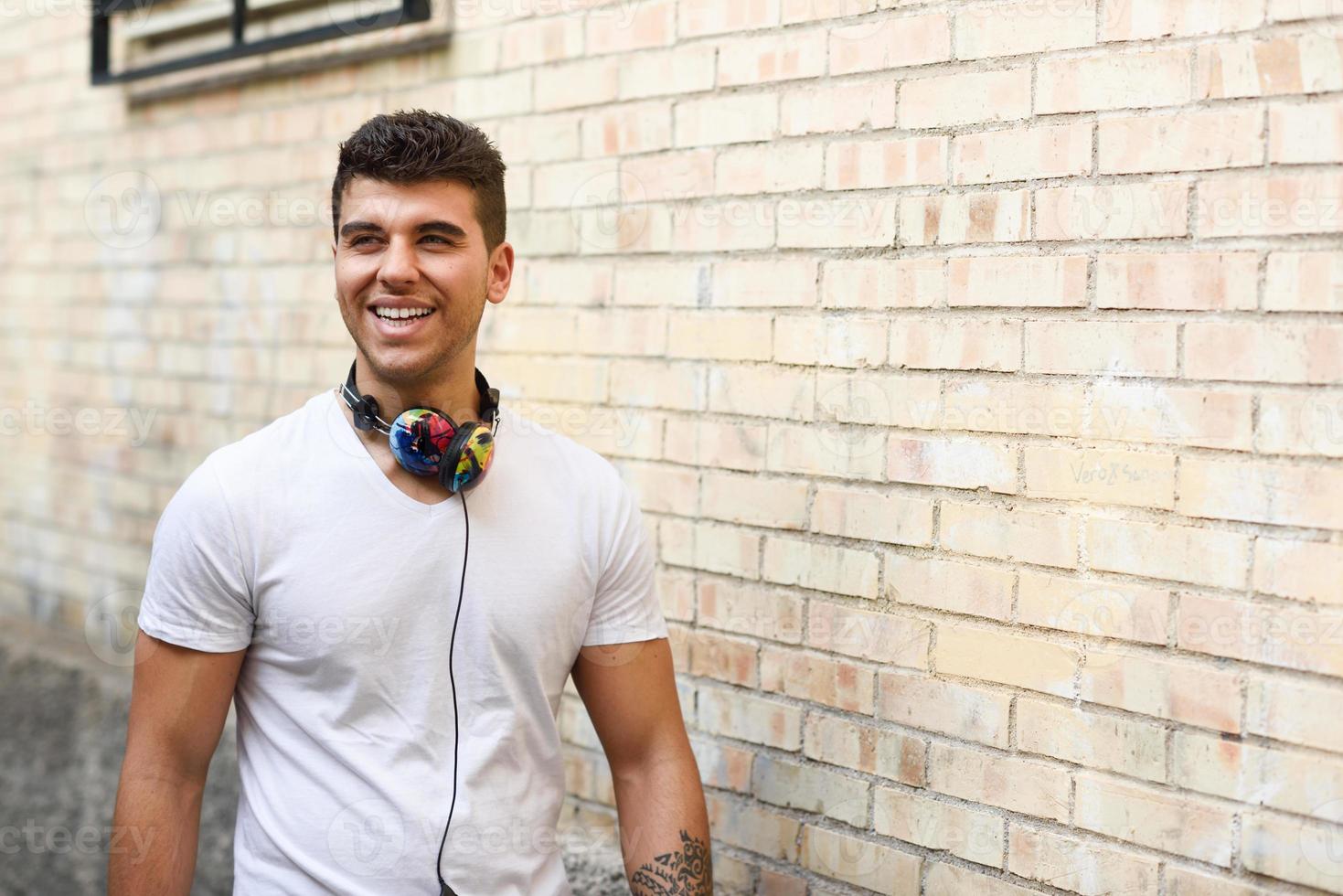 jeune homme en milieu urbain écoutant de la musique avec des écouteurs photo