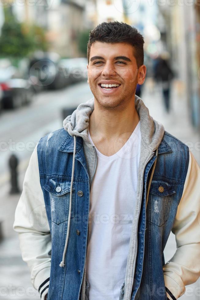 beau jeune homme aux yeux bleus posant près d'un mur photo