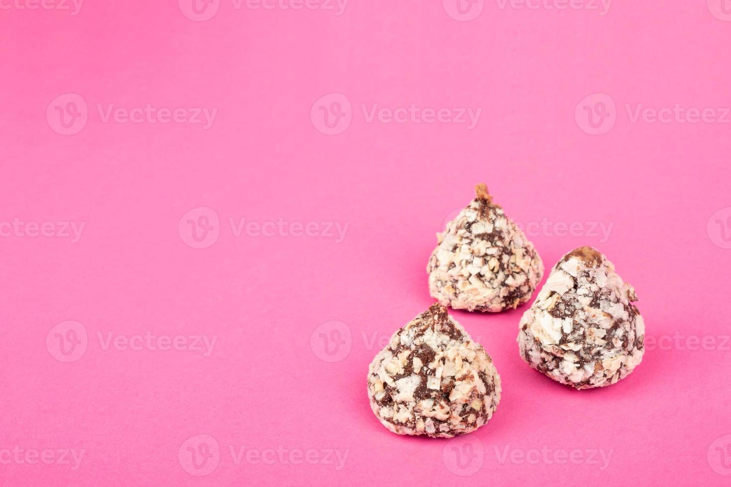 bonbons aux truffes au chocolat avec des noix sur l'espace de copie de fond rose photo