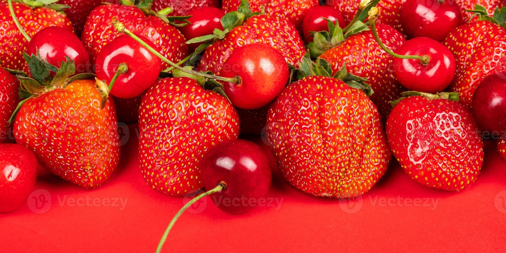 cerise douce et fraises sur fond rouge close up photo