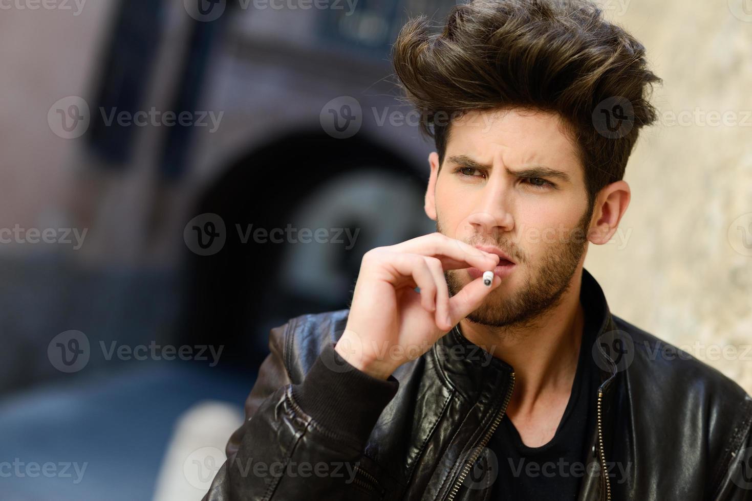 Jeune homme fumant une cigarette en milieu urbain photo