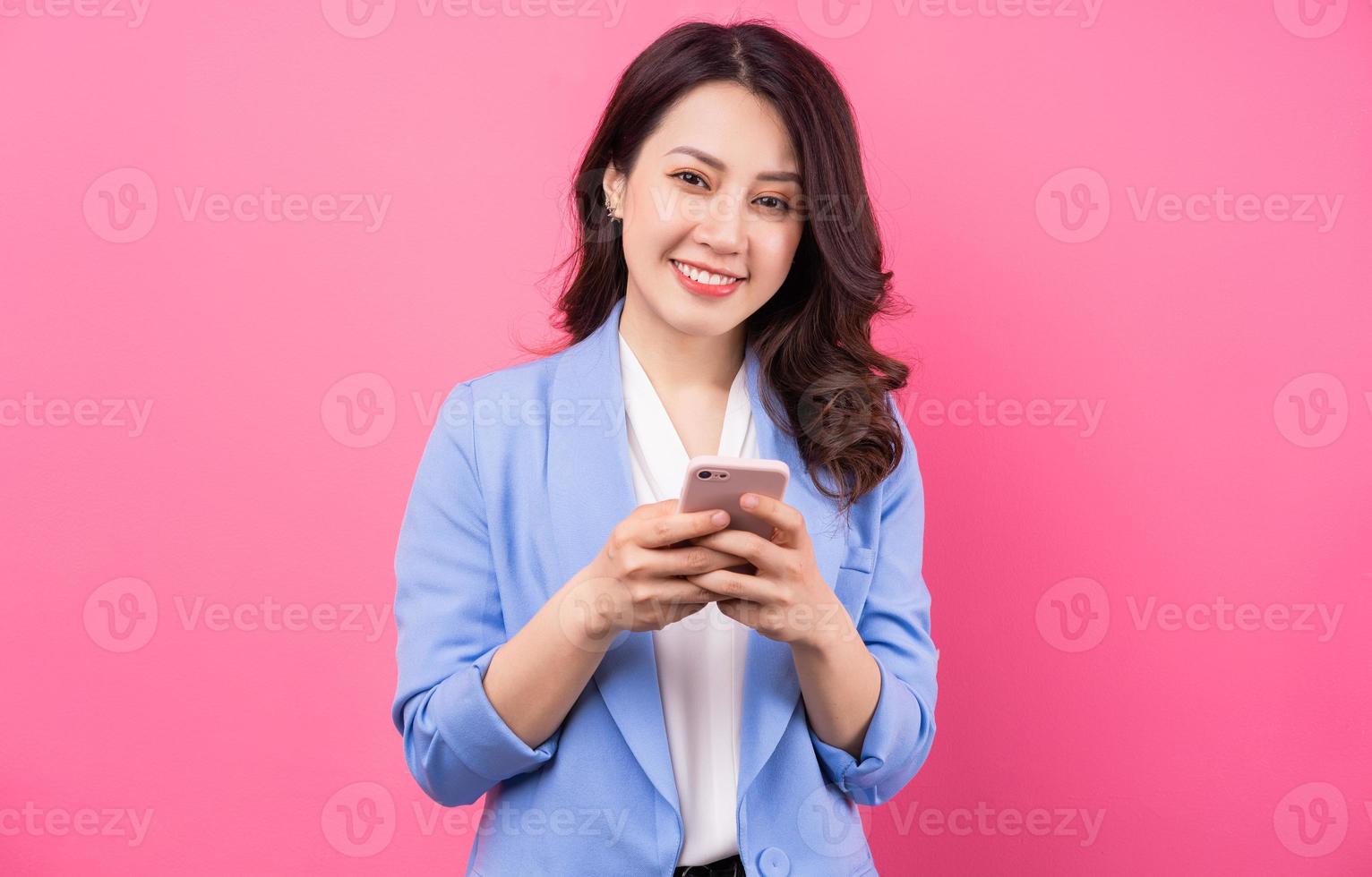 femme d'affaires asiatique utilisant un smartphone sur fond rose photo