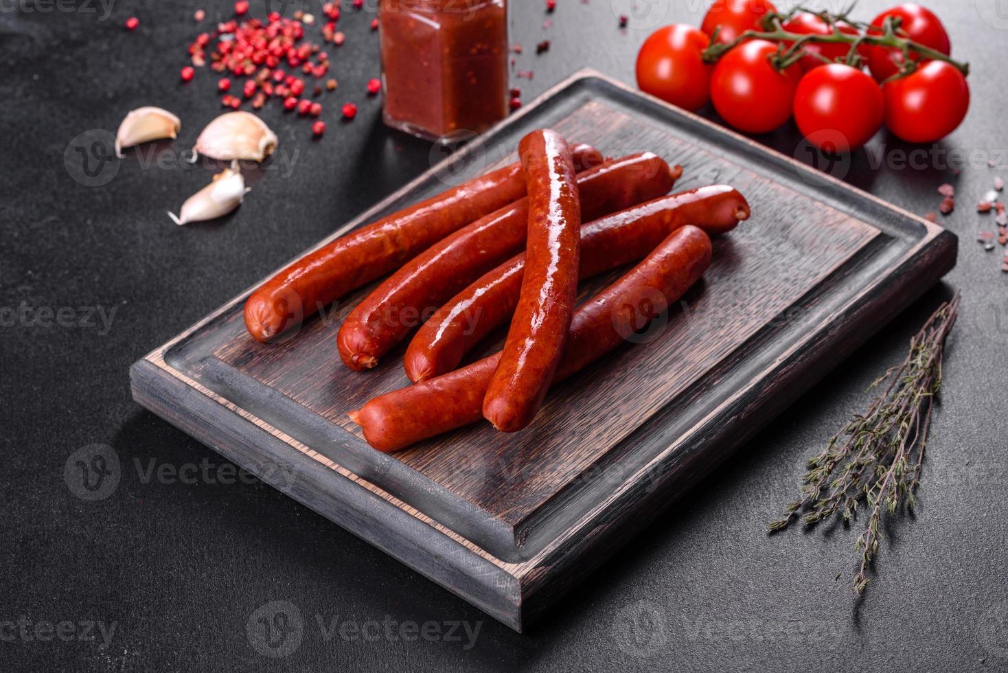 délicieuses saucisses chaudes fumées fraîches et lumineuses avec tomates cerises et sauce tomate photo