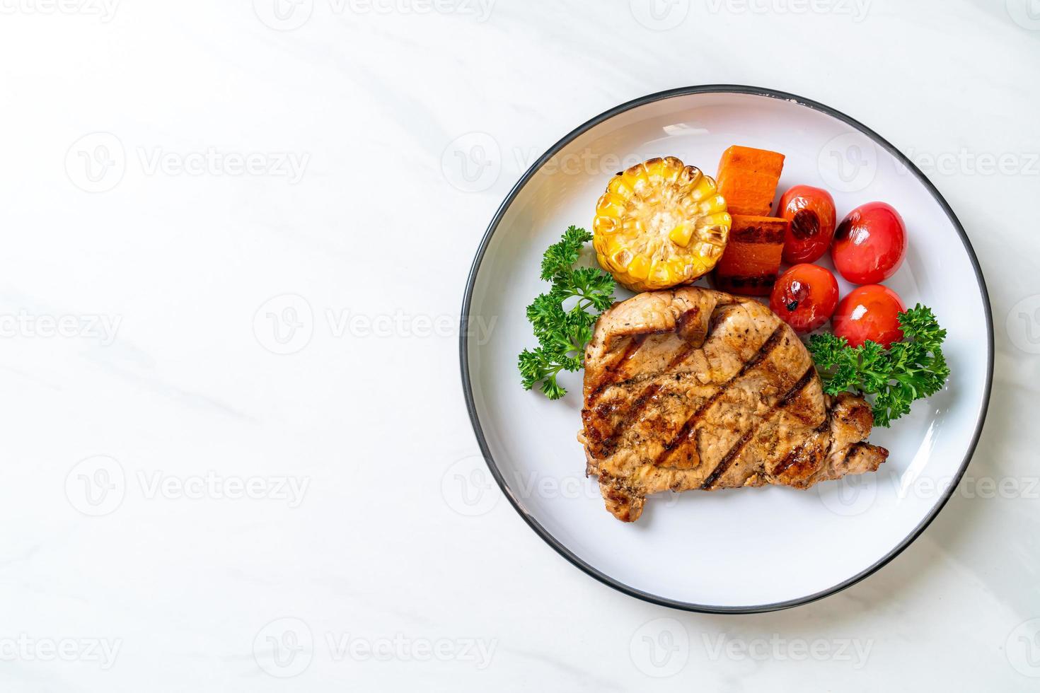 steak de porc grillé et grillé avec maïs, carottes et tomates photo