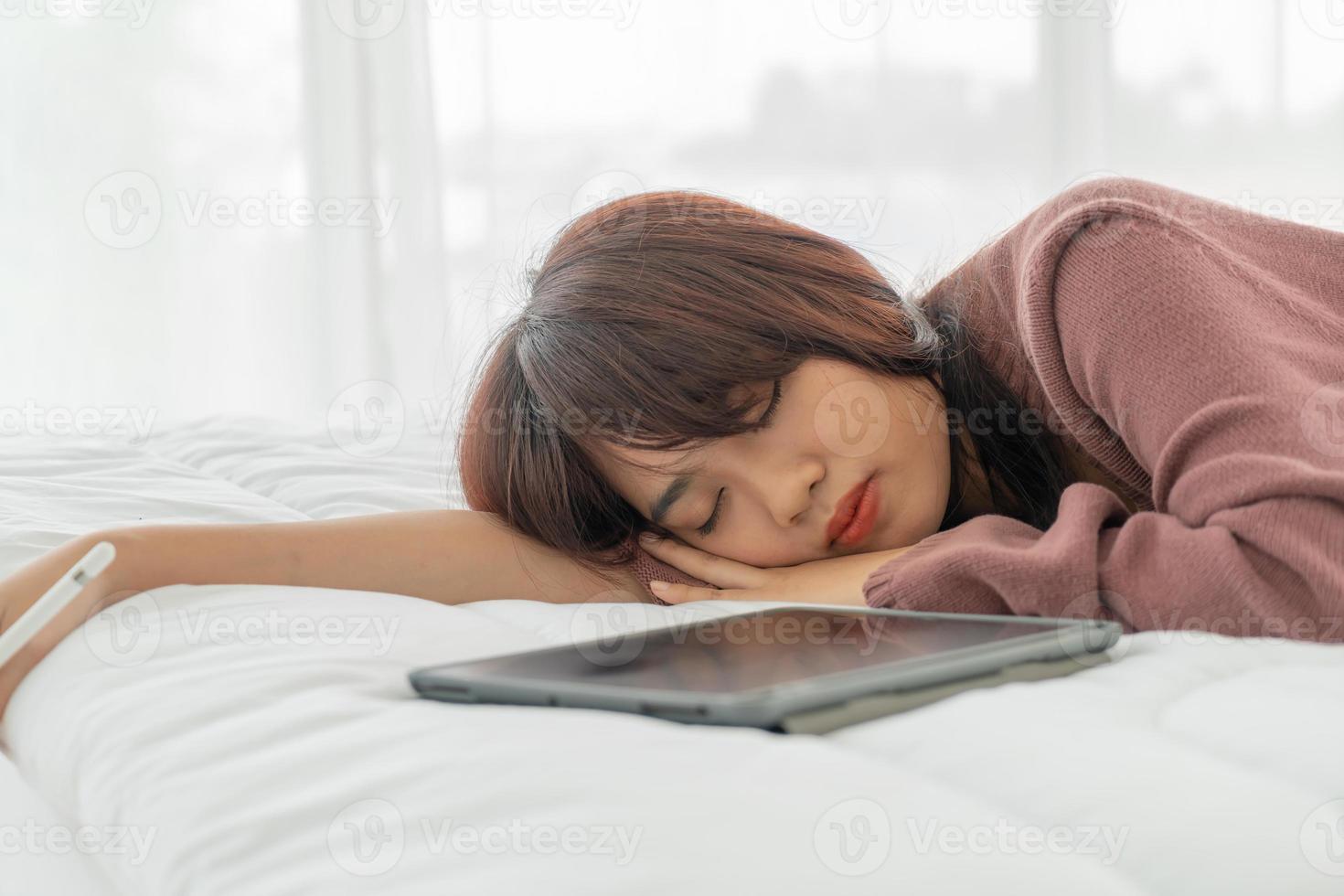 belle femme asiatique travaillant avec tablette sur lit photo